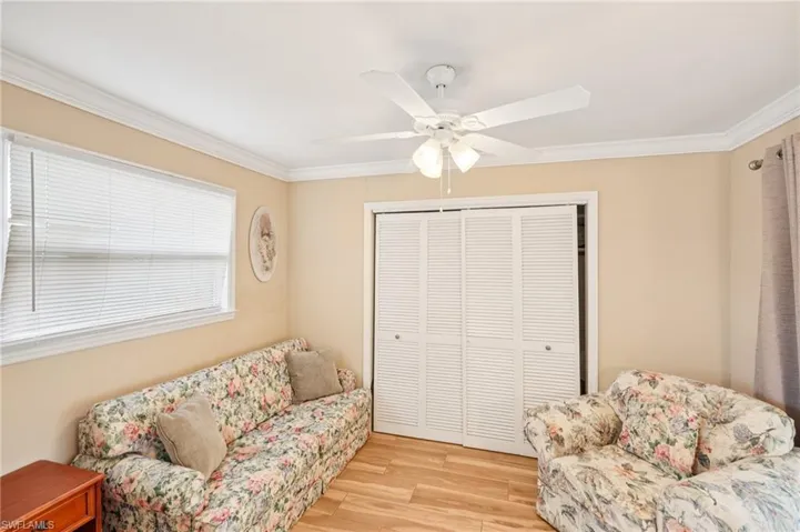 Living area with ornamental molding, light wood-style flooring, and ceiling fan