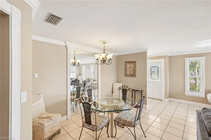 Dining area with crown molding, suspended lighting, and light tile patterned floors