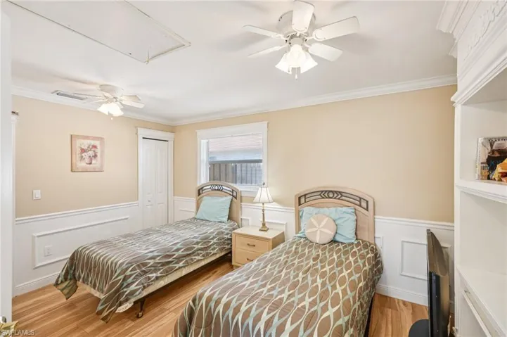 Bedroom with a wainscoted wall, a closet, a ceiling fan, a decorative wall, and light wood-style floors