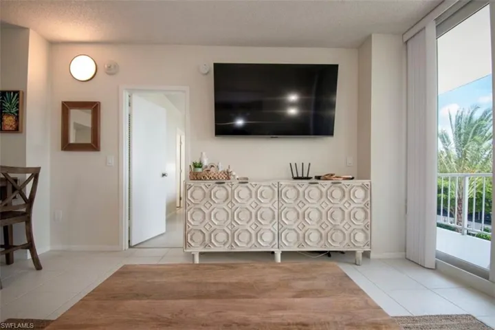 Living room with light tile patterned flooring, a textured ceiling, and expansive windows
