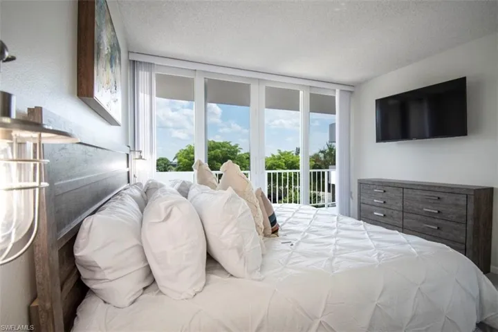 Bedroom featuring a textured ceiling, multiple windows, access to exterior, and floor to ceiling windows