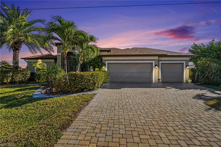 View of front of home with decorative driveway, a garage, stucco siding, and a front lawn