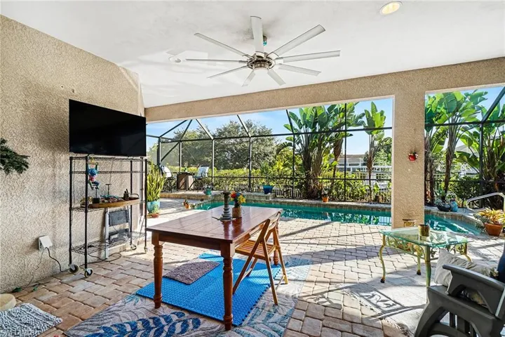 View of patio with an outdoor pool, a sunroom, ceiling fan, and glass enclosure