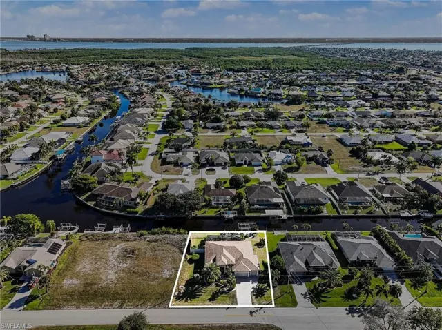 Aerial perspective of suburban area with a large body of water and property boundaries highlighted
