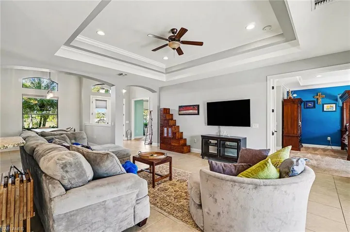 Living room featuring ornamental molding, light tile patterned floors, ceiling fan, recessed lighting, and arched walkways