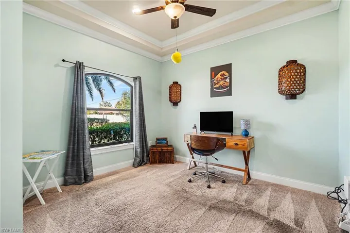 Carpeted home office featuring crown molding and ceiling fan