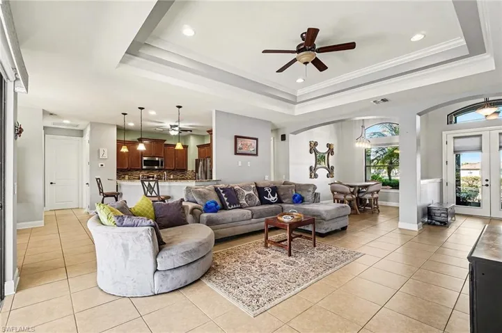 Living room featuring recessed lighting, light tile patterned floors, ornamental molding, a ceiling fan, and arched walkways
