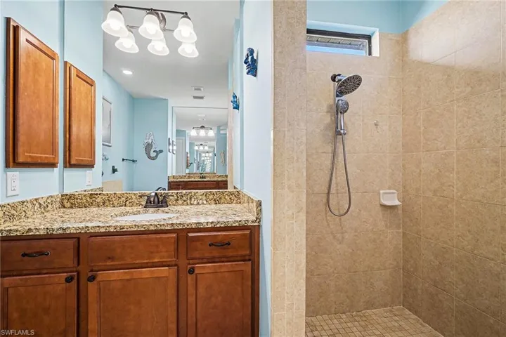 Bathroom featuring tiled shower and vanity