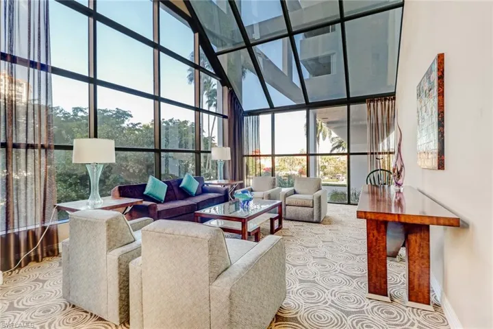 Living room featuring a towering ceiling, expansive windows, and light carpet