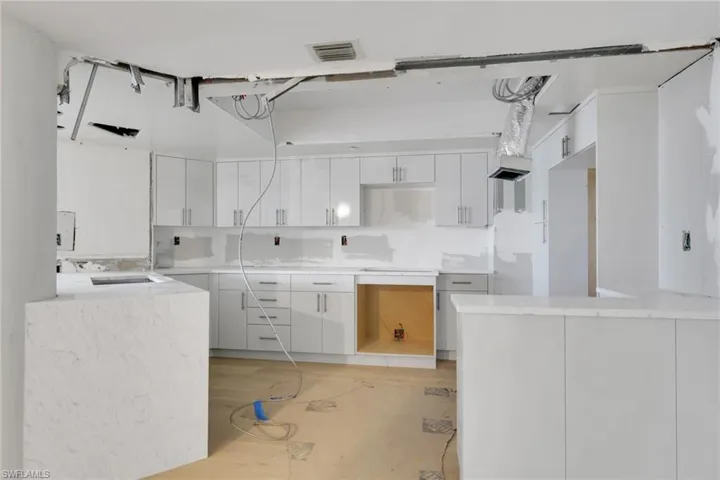 Kitchen with white cabinetry, light stone countertops, modern cabinets, and light wood finished floors