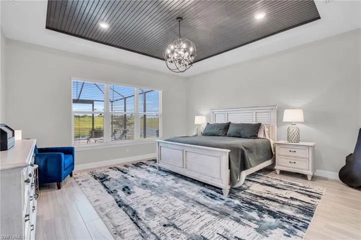 Bedroom with light wood-type flooring, wood ceiling, an inviting chandelier, and a raised ceiling