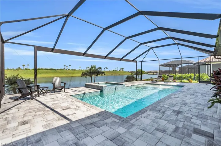 View of swimming pool with a lanai, an in ground hot tub, a water view, and a patio area