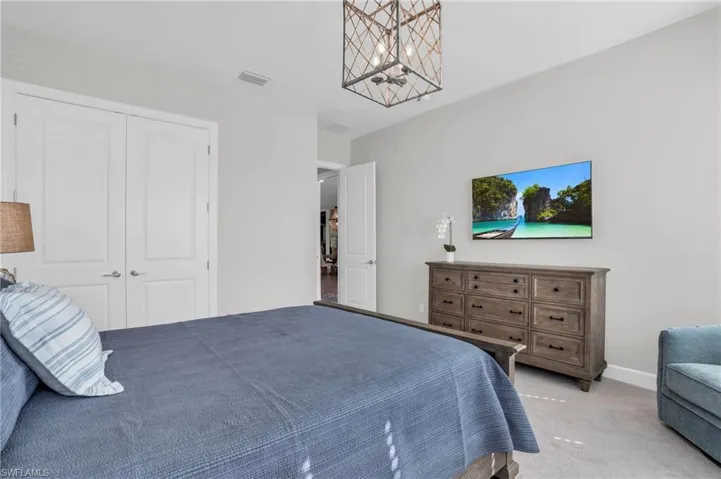 Carpeted bedroom with a closet and an inviting chandelier