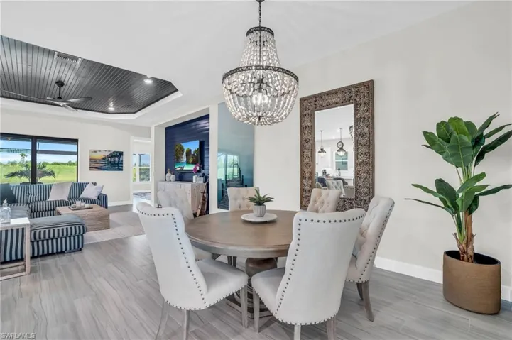 Dining room with ceiling fan with notable chandelier, hardwood / wood-style floors, and a raised ceiling