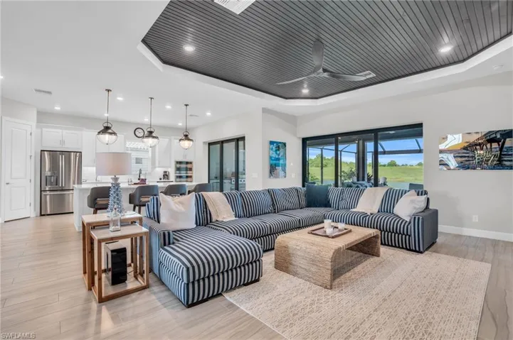 Living room with a tray ceiling, sink, ceiling fan, and light hardwood / wood-style floors