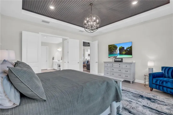 Bedroom with a notable chandelier, a raised ceiling, wood-type flooring, and wooden ceiling