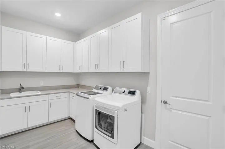 Clothes washing area with sink, washing machine and clothes dryer, and cabinets