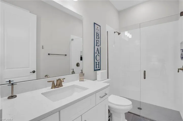Bathroom featuring an enclosed shower, vanity, and toilet