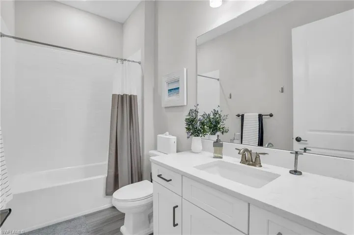 Full bathroom featuring toilet, shower / tub combo with curtain, and vanity