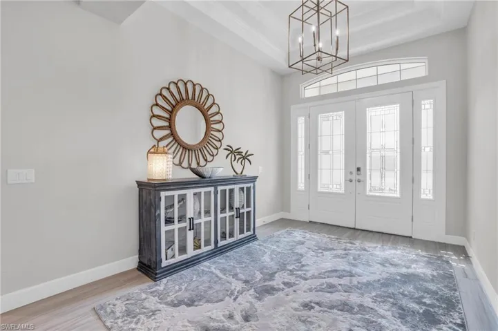 Entryway featuring a notable chandelier, a raised ceiling, french doors, and hardwood / wood-style flooring