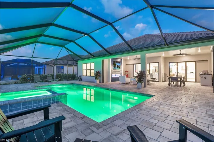 View of pool with glass enclosure, a patio, an in ground hot tub, and ceiling fan