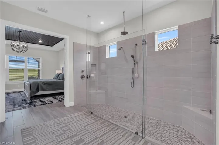 Bathroom with tiled shower, a chandelier, and tile patterned flooring