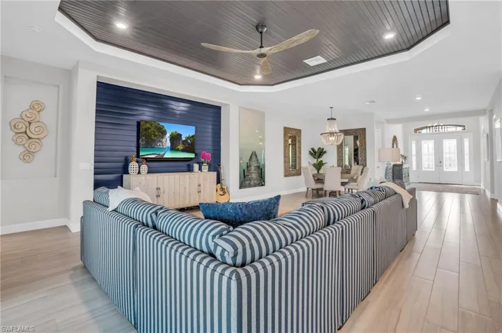 Living room with ceiling fan, light hardwood / wood-style floors, and a tray ceiling