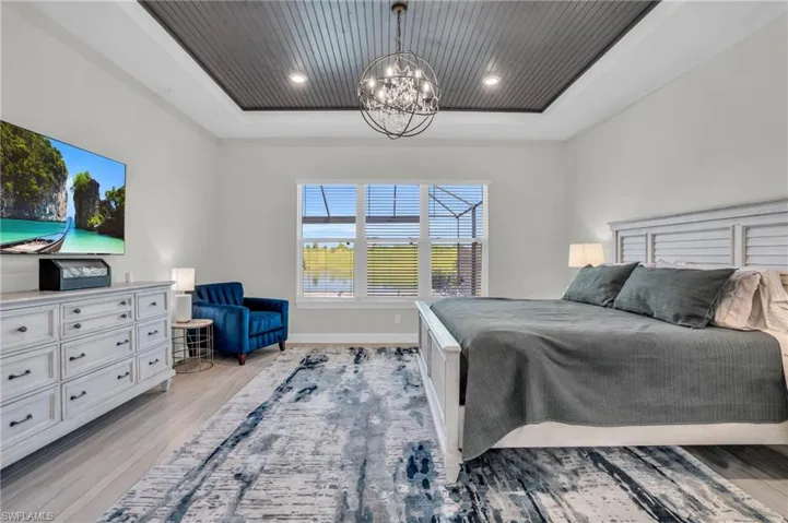 Bedroom featuring a notable chandelier, a tray ceiling, and light hardwood / wood-style floors