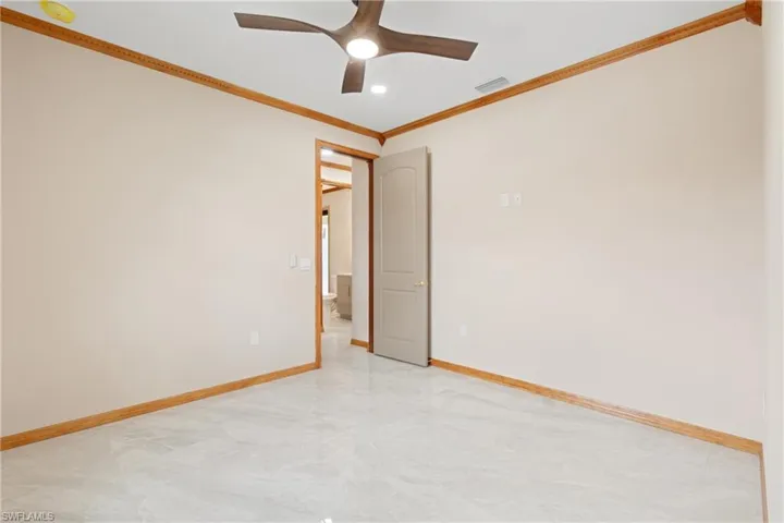 Spare room featuring tile patterned floors, crown molding, and ceiling fan