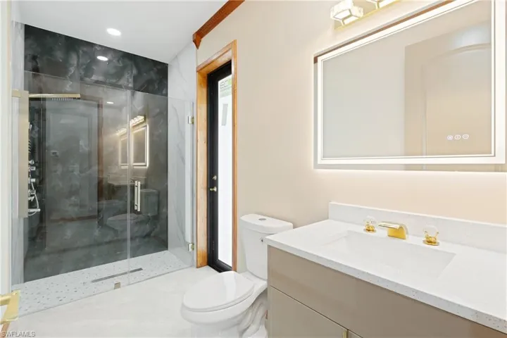 Bathroom featuring vanity, a shower with door, and toilet