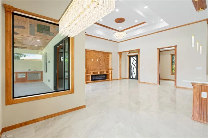 Unfurnished living room featuring ornamental molding, tile patterned floors, and a tray ceiling
