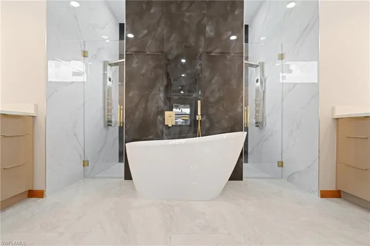 Bathroom featuring independent shower and bath, vanity, tile patterned flooring, and tile walls