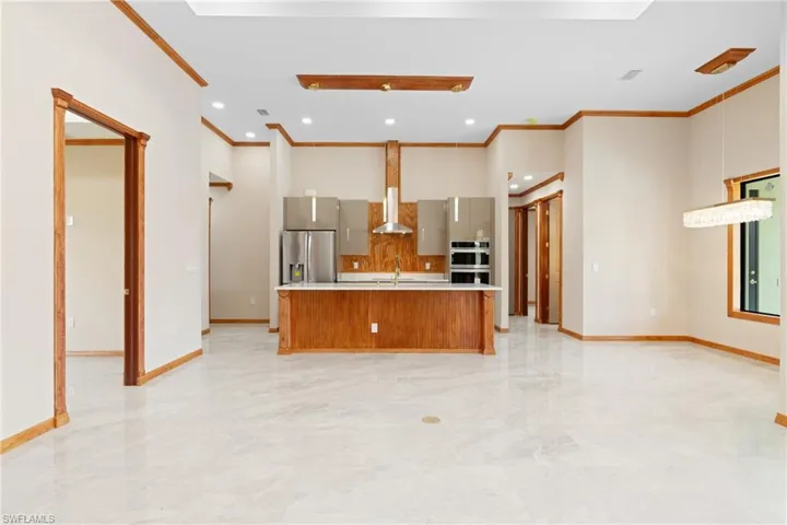 Kitchen with light tile patterned flooring, stainless steel appliances, backsplash, and an island with sink