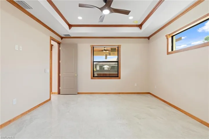Empty room featuring a tray ceiling, ceiling fan, carpet flooring, and ornamental molding