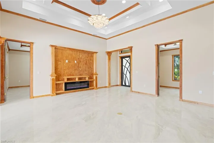 Unfurnished living room featuring light tile patterned floors, crown molding, and a tray ceiling