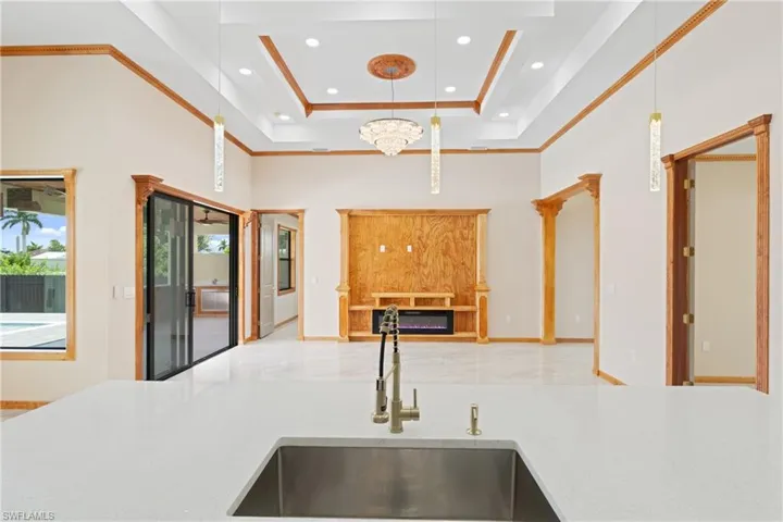 Kitchen featuring sink, a towering ceiling, a raised ceiling, and light tile patterned floors