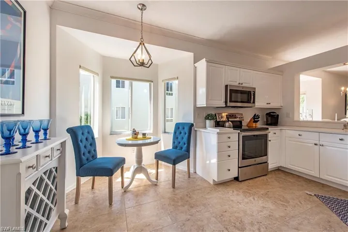 Kitchen featuring hanging light fixtures, white cabinetry, stainless steel appliances, and a chandelier
