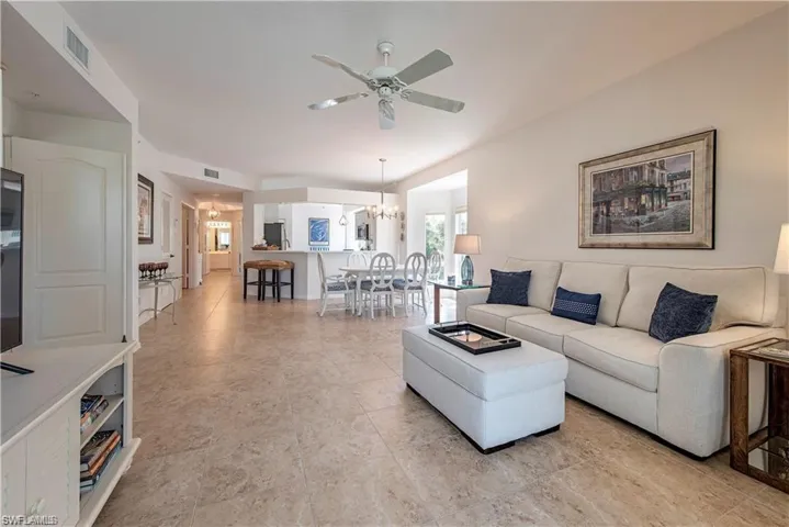 Living room with ceiling fan with notable chandelier and visible vents