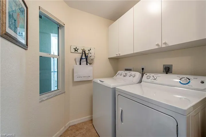 Clothes washing area with cabinet space, washing machine and dryer, and baseboards