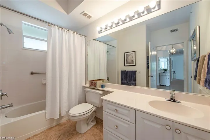 Bathroom featuring vanity, tile patterned flooring, visible vents, and shower / bathtub combination with curtain