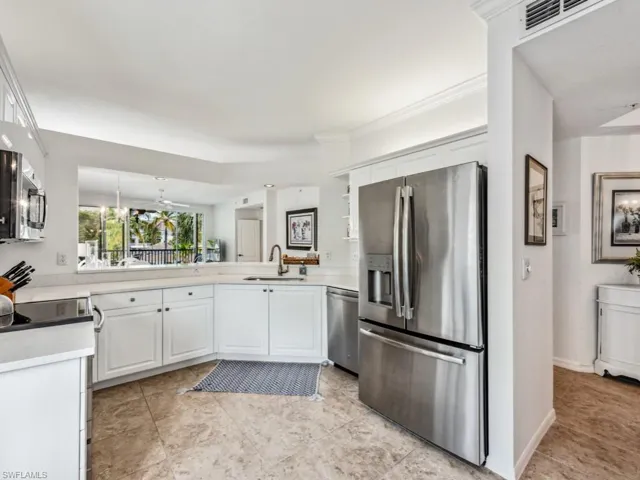 Kitchen featuring stainless steel appliances, light countertops, visible vents, white cabinets, and a sink