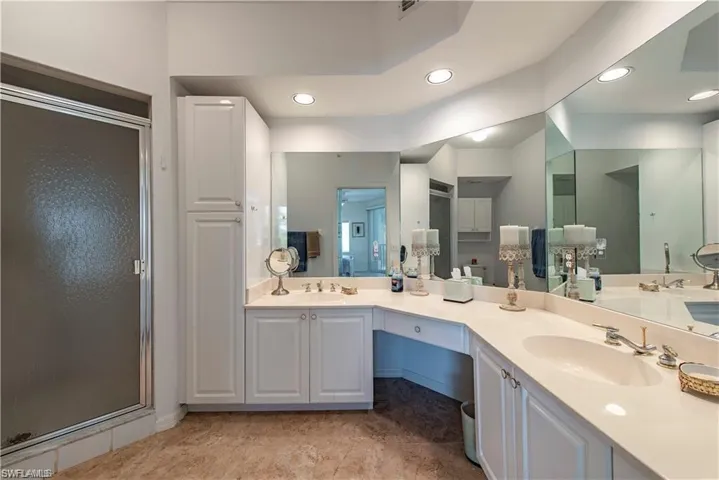 Bathroom with recessed lighting, a sink, a shower stall, and double vanity