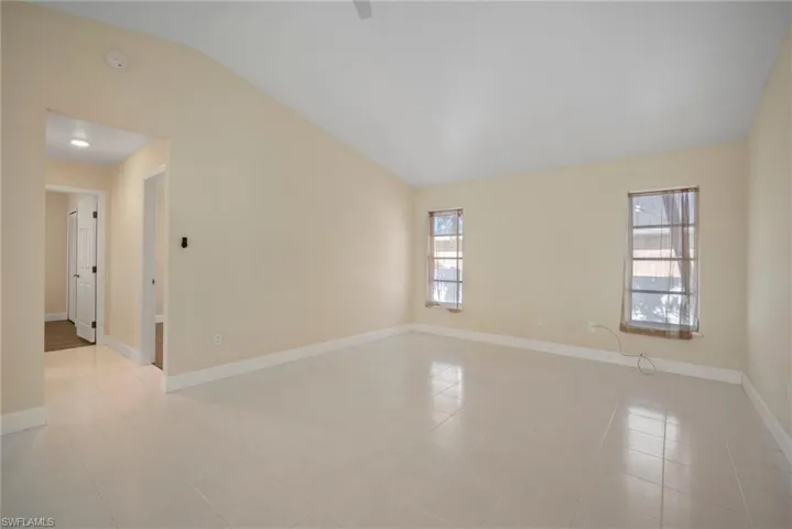 Spare room with light tile patterned floors, baseboards, and vaulted ceiling