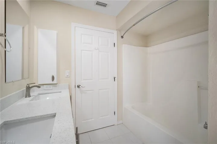 Bathroom with vanity, tub / shower combination, tile patterned flooring, and visible vents
