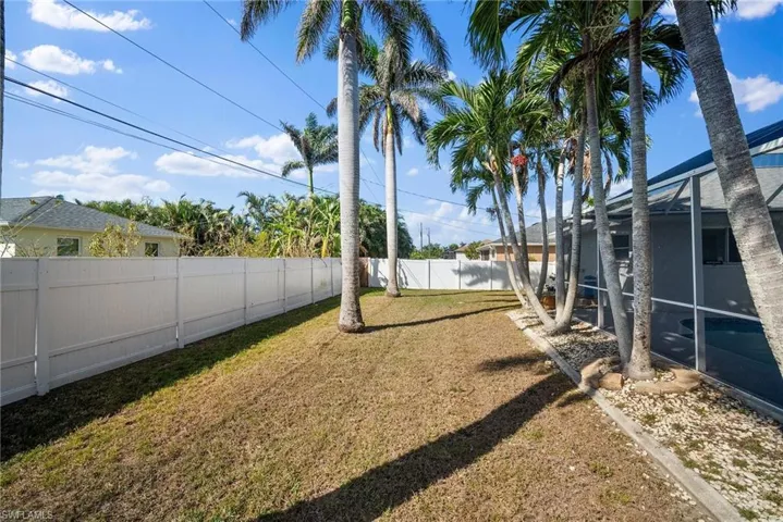View of yard featuring glass enclosure and a fenced backyard
