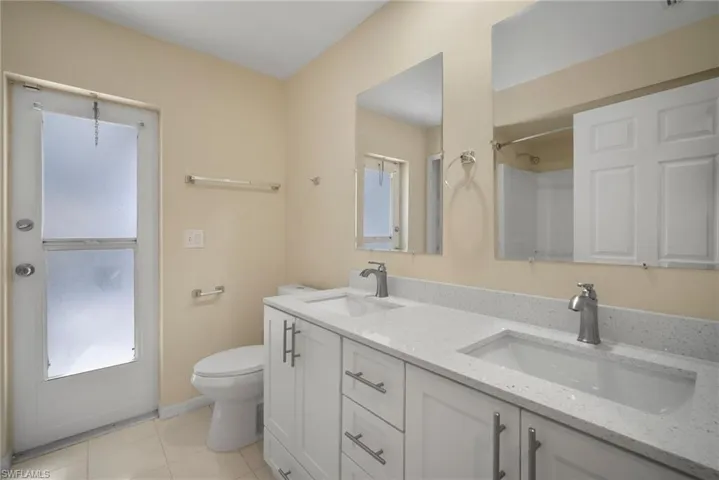 Full bath with double vanity, a sink, toilet, and tile patterned floors