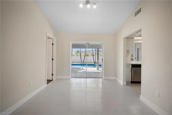 Spare room with vaulted ceiling, light tile patterned flooring, visible vents, and baseboards