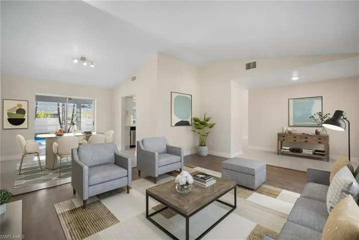 Living room with lofted ceiling, baseboards, visible vents, and wood finished floors