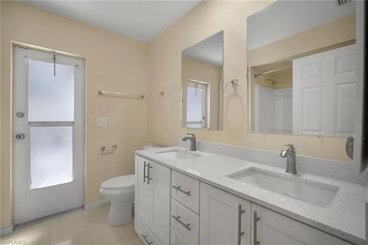 Bathroom with tile patterned flooring, a sink, toilet, and double vanity