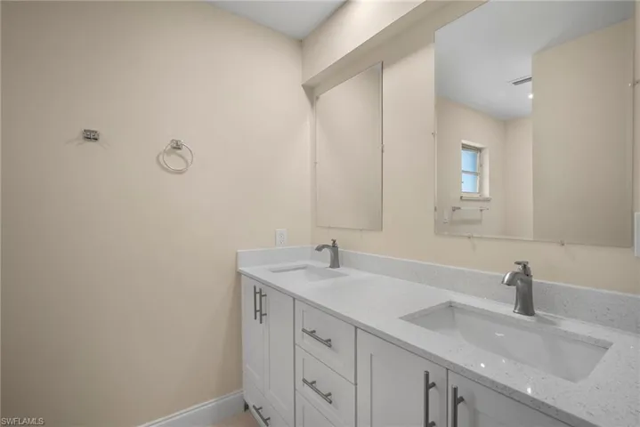 Bathroom with double vanity, baseboards, and a sink